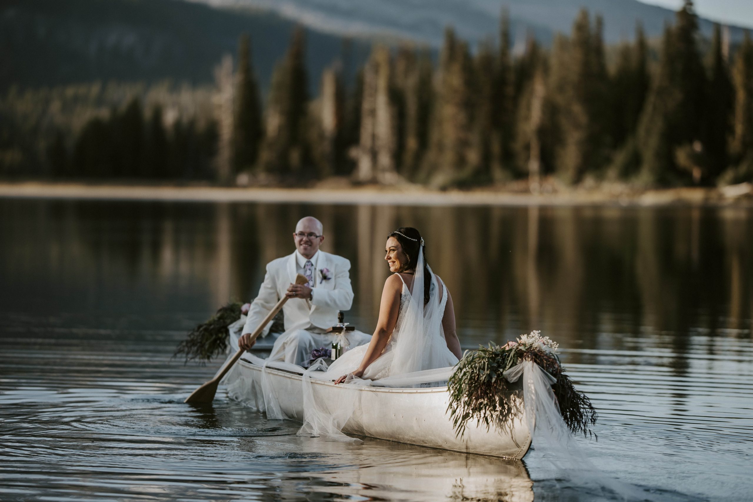 two people sitting in a canoe in the mountains in colorado after getting married