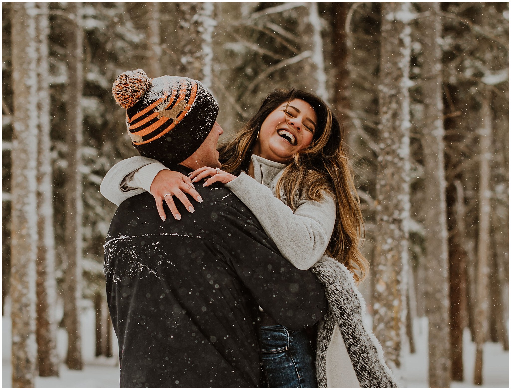 Woman laughing in the arms of her boyfriend after they are engaged. It is snowing in Breckenridge